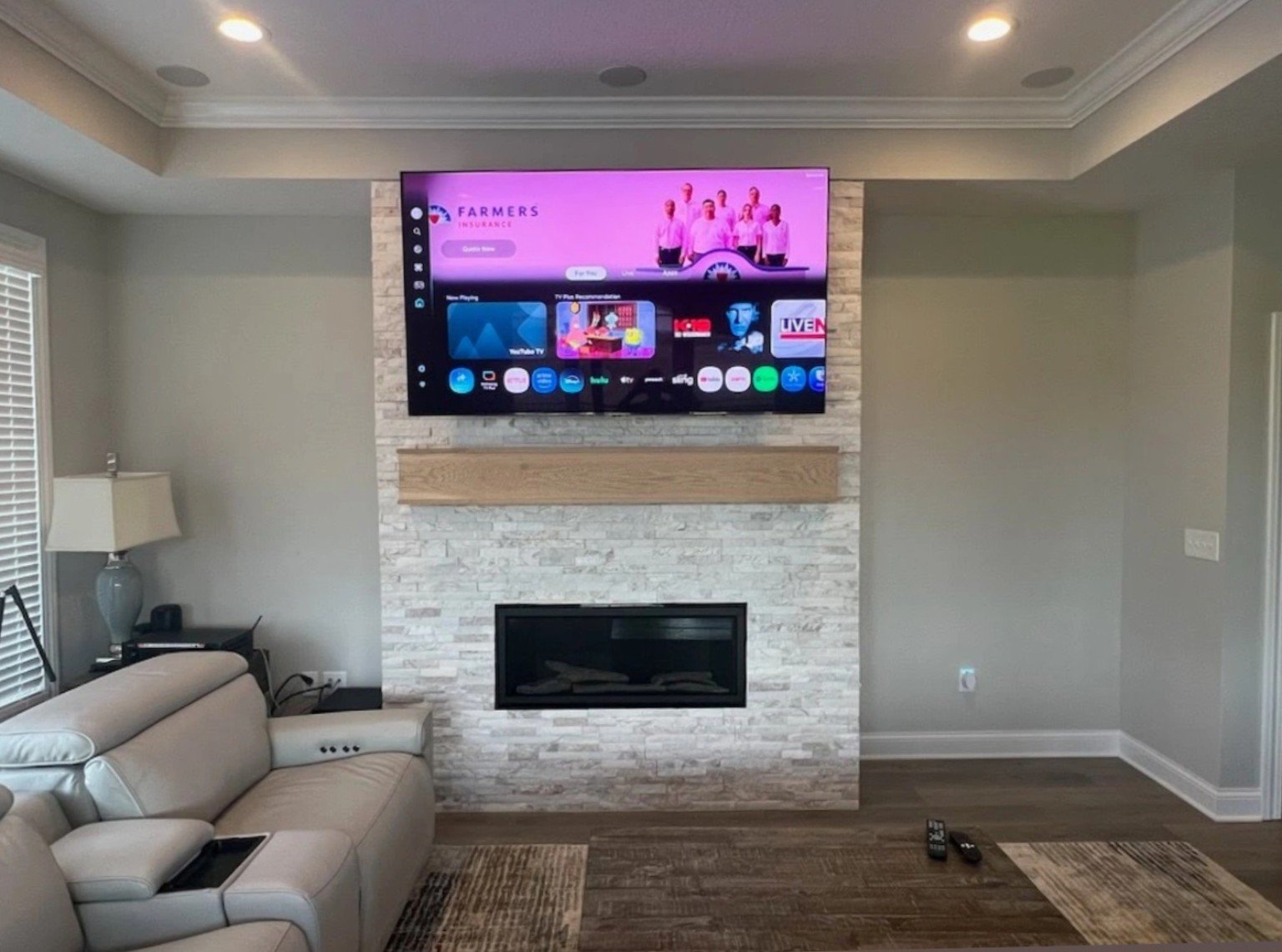 TV mounted above a white stone fireplace and timber mantel